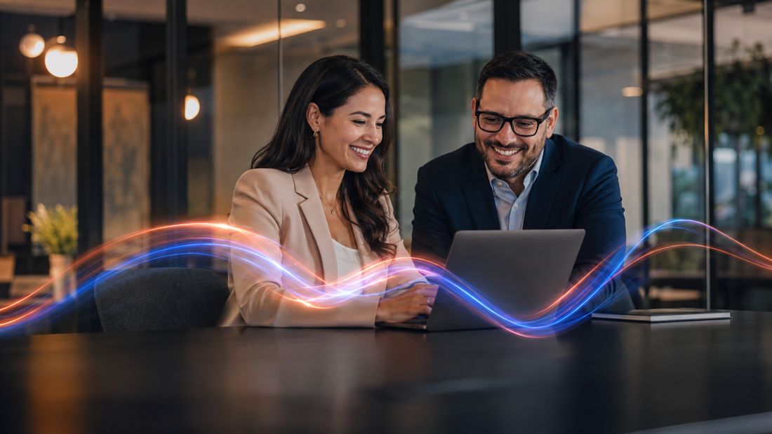Two professionals collaborating at a laptop with digital light waves